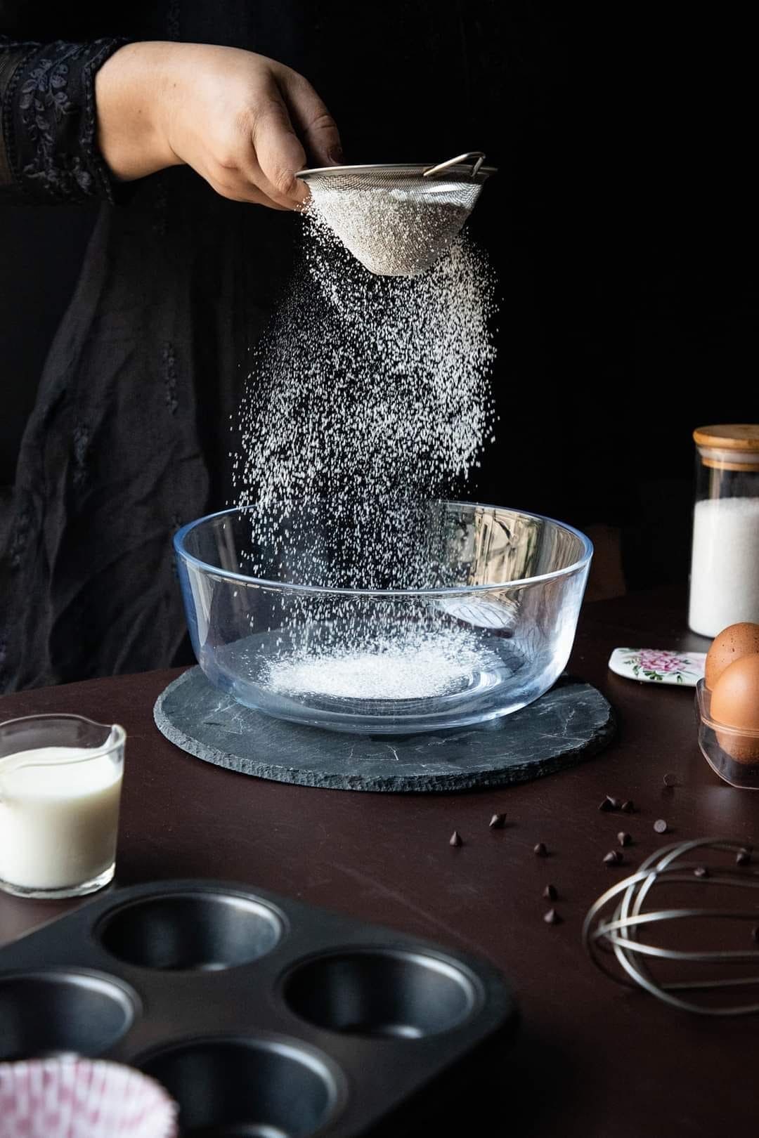 Hand pouring sugar into a bowl